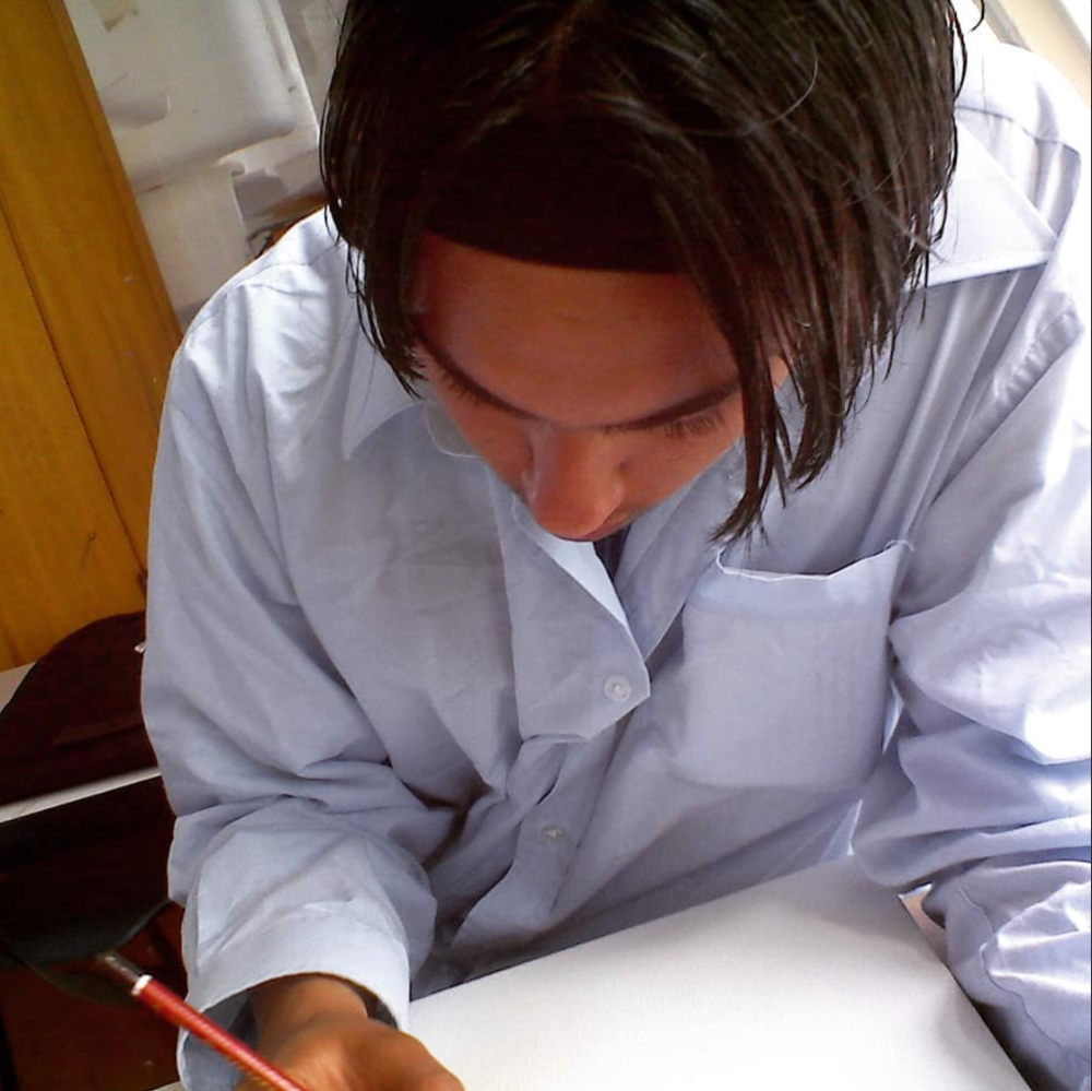 Jay, age 14, drawing at his desk in Year 10 Graphics